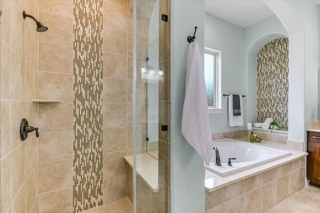 bathroom with a garden tub, tiled shower, and vanity