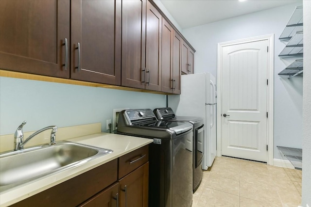 washroom featuring cabinet space, light tile patterned floors, washer and clothes dryer, and a sink