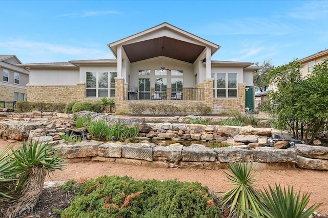 back of house featuring stone siding, fence, and stucco siding