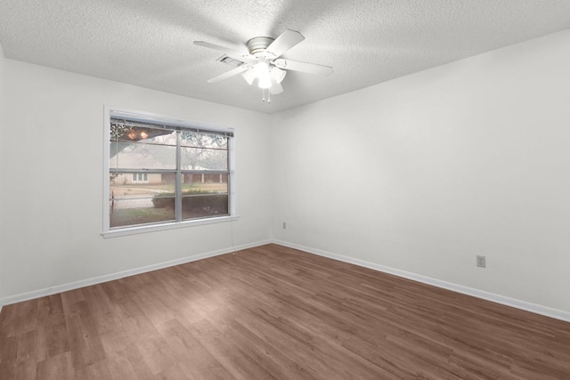 spare room featuring dark wood-type flooring, a textured ceiling, baseboards, and a ceiling fan