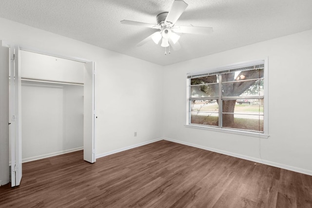 unfurnished bedroom featuring baseboards, ceiling fan, dark wood-style flooring, a textured ceiling, and a closet