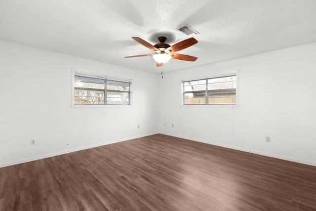 unfurnished room with baseboards, visible vents, a ceiling fan, dark wood-style flooring, and a textured ceiling