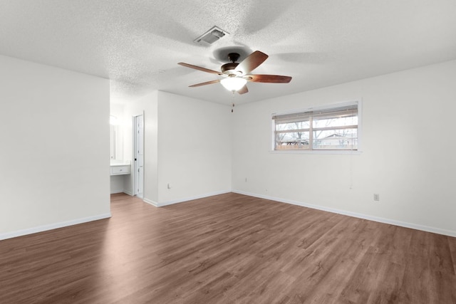 unfurnished room with visible vents, a ceiling fan, a textured ceiling, wood finished floors, and baseboards