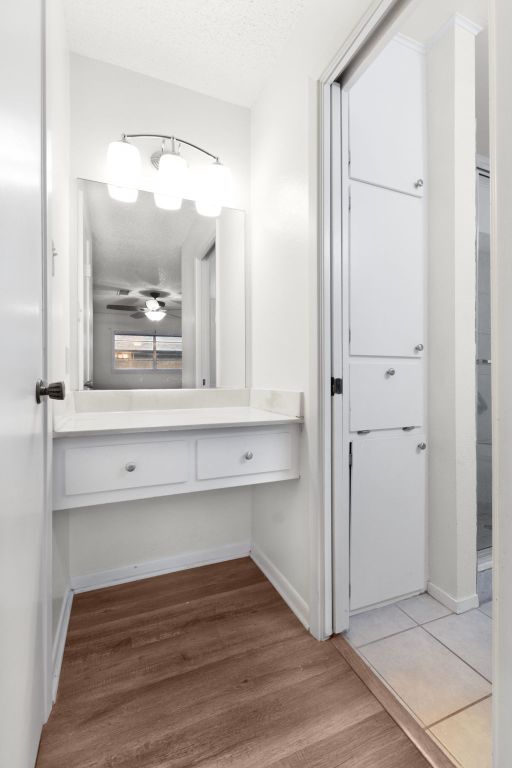 bathroom with a textured ceiling, wood finished floors, vanity, and baseboards