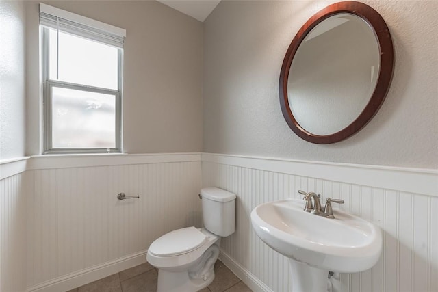 bathroom featuring tile patterned flooring, wainscoting, a sink, and toilet