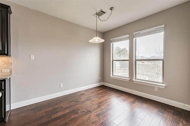 unfurnished dining area featuring dark wood-type flooring and baseboards