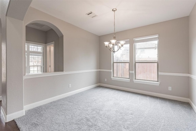 unfurnished room with baseboards, visible vents, arched walkways, carpet floors, and a chandelier