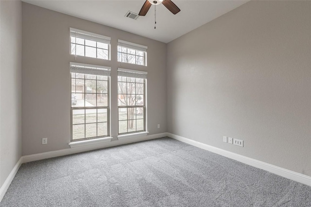 empty room featuring light carpet, a ceiling fan, visible vents, and baseboards