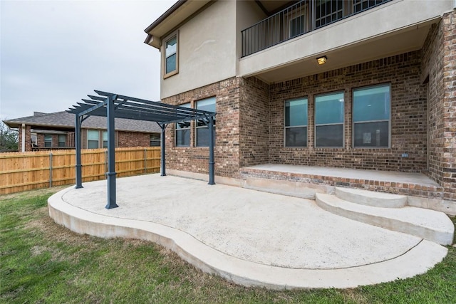 view of patio with a balcony, fence, and a pergola