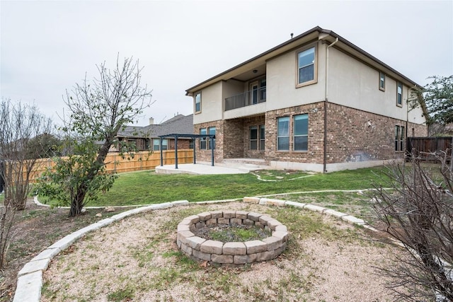 rear view of property with fence private yard, a balcony, brick siding, stucco siding, and a patio area