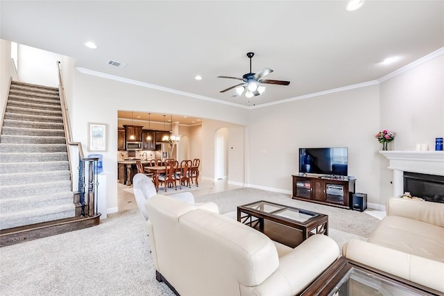 living room with light carpet, arched walkways, ornamental molding, stairs, and recessed lighting