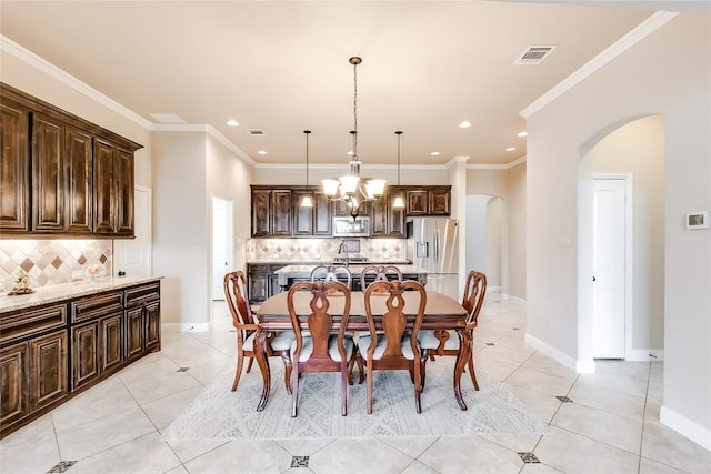 dining area with arched walkways, light tile patterned floors, visible vents, ornamental molding, and baseboards