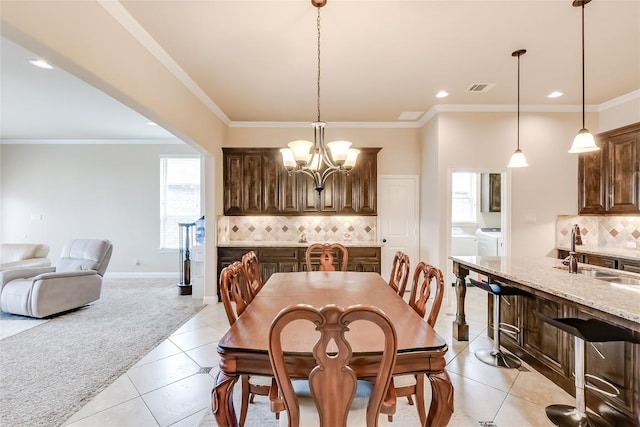 dining area with a chandelier, light colored carpet, visible vents, ornamental molding, and independent washer and dryer