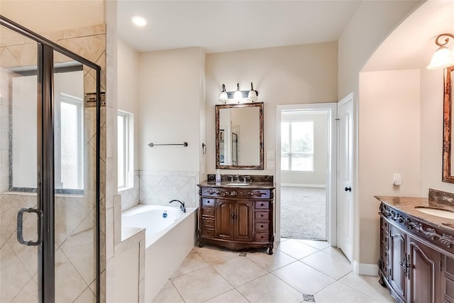 bathroom with a garden tub, two vanities, a sink, tile patterned floors, and a stall shower