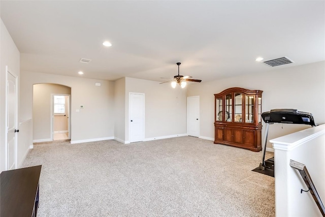 interior space featuring arched walkways, recessed lighting, light colored carpet, visible vents, and baseboards