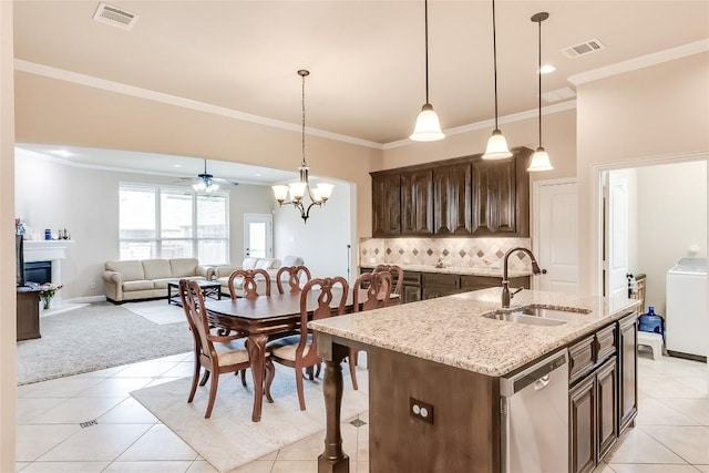 kitchen with a center island with sink, visible vents, stainless steel dishwasher, a sink, and washer / dryer