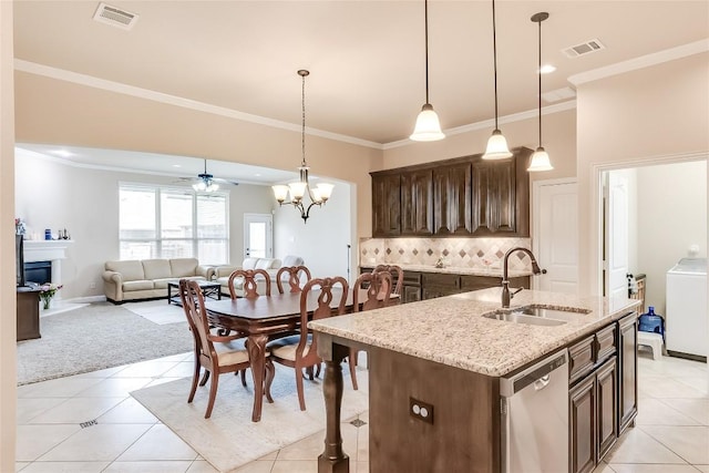 1312 Mustang Brook Ln, Leander, TX 78641 - kitchen featuring dishwasher, washer / dryer, dark brown cabinets, ornamental molding, and a kitchen island with sink