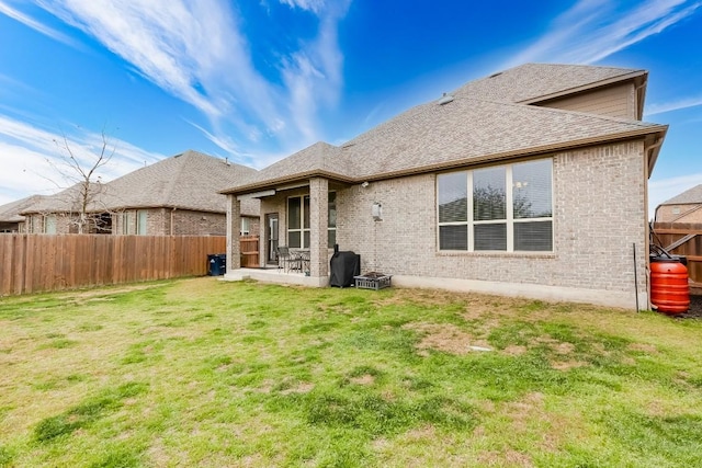 1312 Mustang Brook Ln, Leander, TX 78641 - rear view of house featuring a fenced backyard, brick siding, a shingled roof, and a patio area