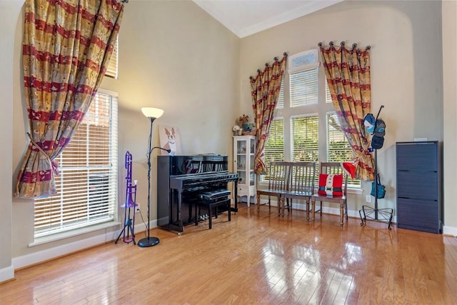 sitting room with baseboards, a high ceiling, and wood finished floors