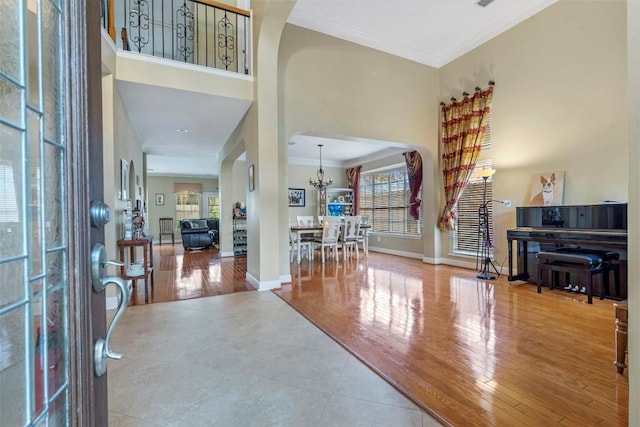 foyer with baseboards, a high ceiling, wood finished floors, and crown molding