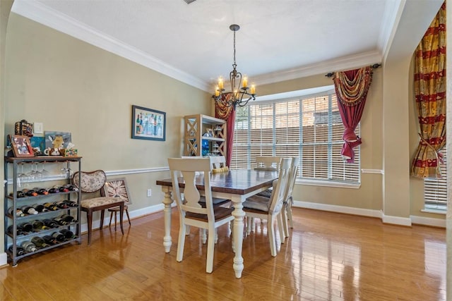 dining room with a notable chandelier, light wood-style floors, baseboards, and crown molding