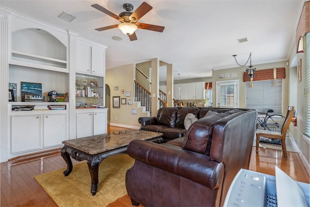 living room featuring light wood-style floors, ceiling fan, stairway, and visible vents