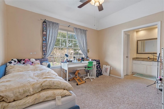 bedroom with ceiling fan, ensuite bathroom, light colored carpet, baseboards, and vaulted ceiling