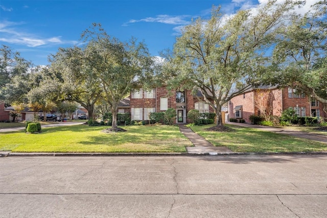 townhome / multi-family property with a front yard and brick siding