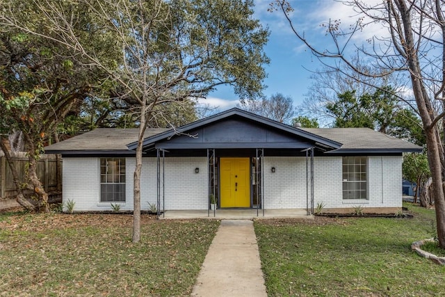 view of front of house featuring covered porch, brick siding, a front lawn, and fence