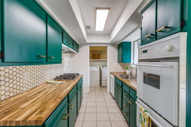 400 Cherry Hill Dr, Austin, TX 78704 - kitchen featuring washing machine and clothes dryer, stainless steel gas stovetop, green cabinetry, and butcher block countertops