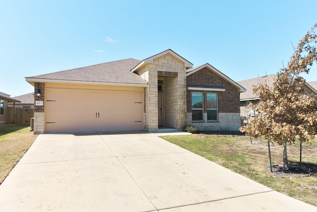 view of front of house with brick siding, an attached garage, stone siding, driveway, and a front lawn