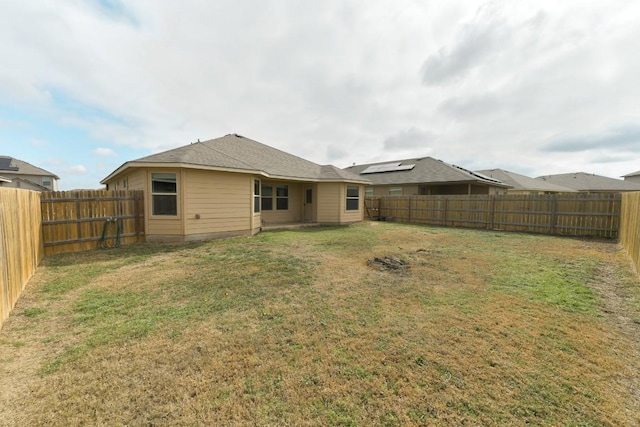 rear view of property with a fenced backyard and a lawn