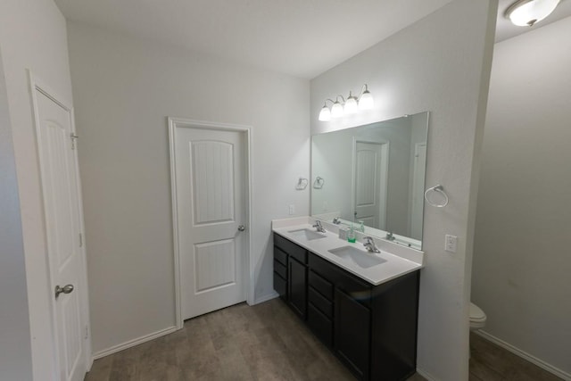 full bath featuring wood finished floors, a sink, toilet, and double vanity