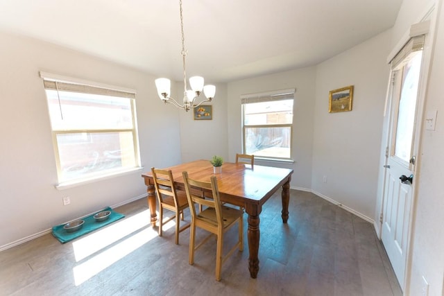 dining space featuring dark wood-style flooring, an inviting chandelier, and baseboards