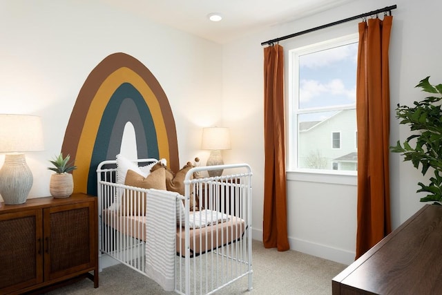 bedroom with a nursery area, light colored carpet, and baseboards