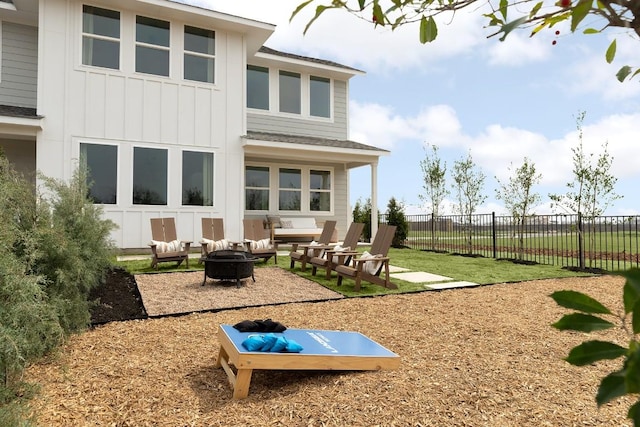 rear view of house featuring fence, a fire pit, and board and batten siding