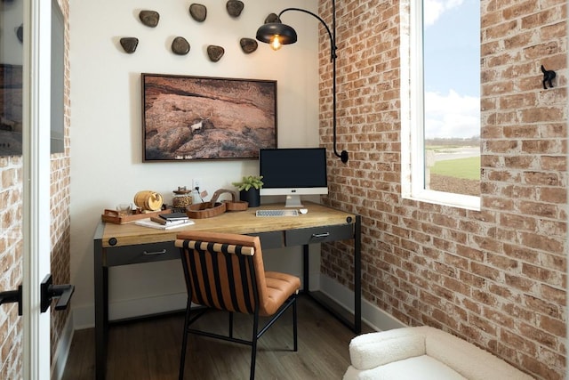 office area featuring baseboards, dark wood finished floors, and brick wall