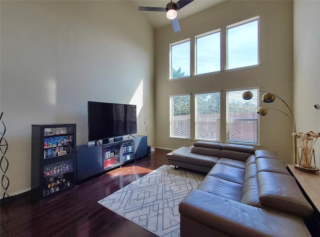 living area featuring a ceiling fan, dark wood-style flooring, and baseboards