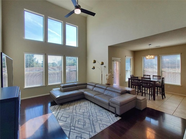 living area with ceiling fan with notable chandelier, plenty of natural light, baseboards, and wood finished floors