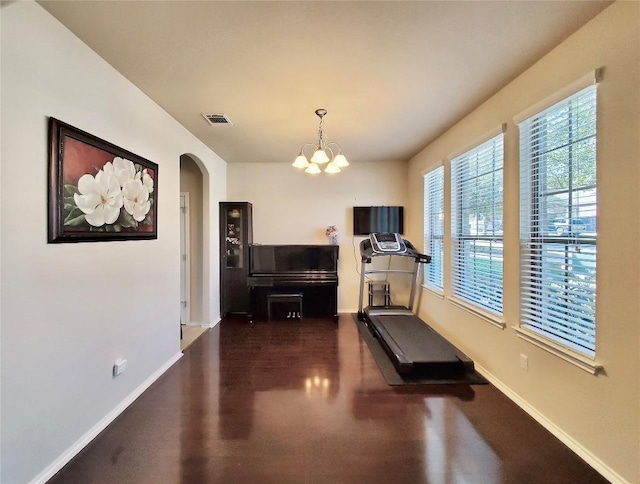 exercise room with arched walkways, visible vents, dark wood finished floors, and baseboards