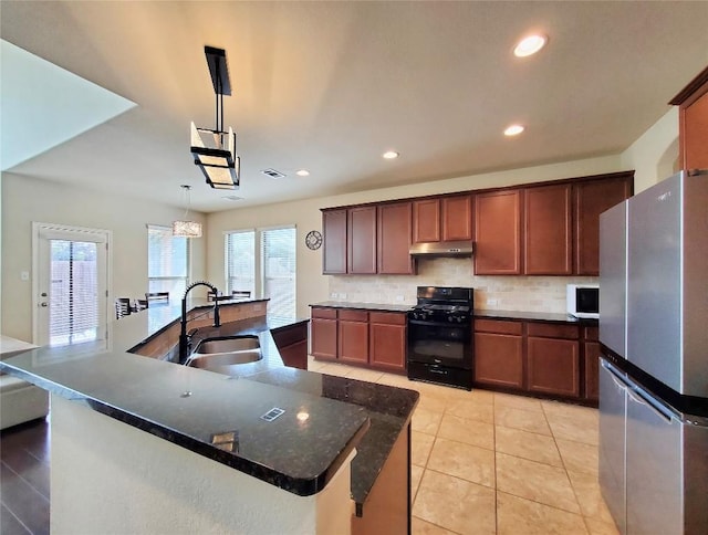 kitchen featuring under cabinet range hood, a sink, freestanding refrigerator, gas stove, and pendant lighting