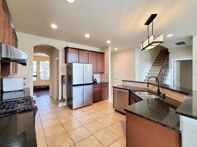 kitchen with arched walkways, stainless steel appliances, a sink, visible vents, and pendant lighting