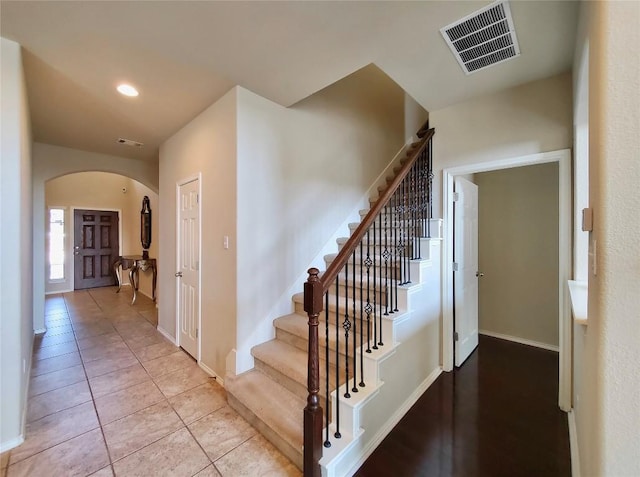 stairs with recessed lighting, visible vents, arched walkways, and tile patterned floors