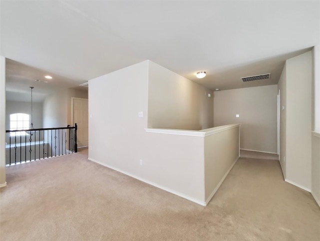 unfurnished room featuring light carpet, an inviting chandelier, visible vents, and baseboards