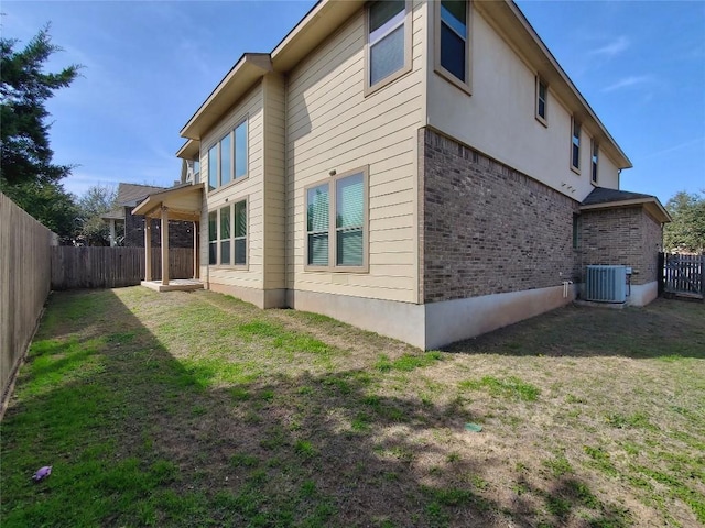 view of property exterior featuring cooling unit, brick siding, a yard, and a fenced backyard