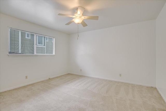 empty room featuring light carpet, baseboards, and a ceiling fan