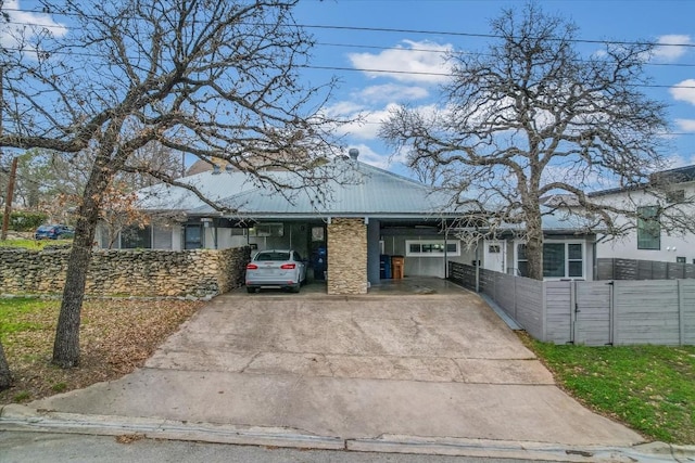 view of front of home with concrete driveway, a carport, and fence