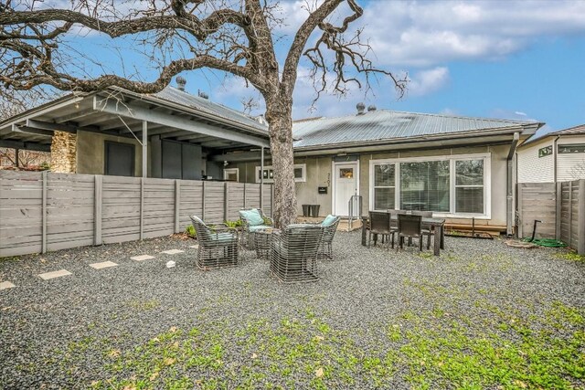 rear view of property with a patio area, a fenced backyard, metal roof, and stucco siding