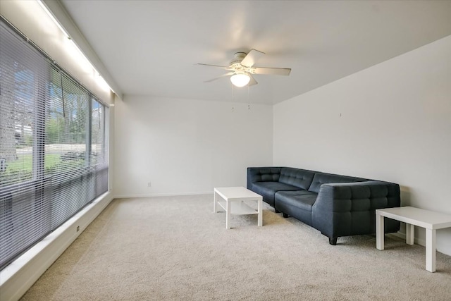 living room featuring ceiling fan, baseboards, and light colored carpet