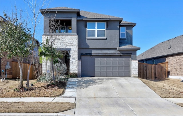 prairie-style house featuring a garage, stone siding, fence, and driveway